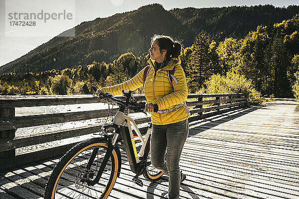 Lächelnde Frau  die Fahrrad auf Brücke dreht