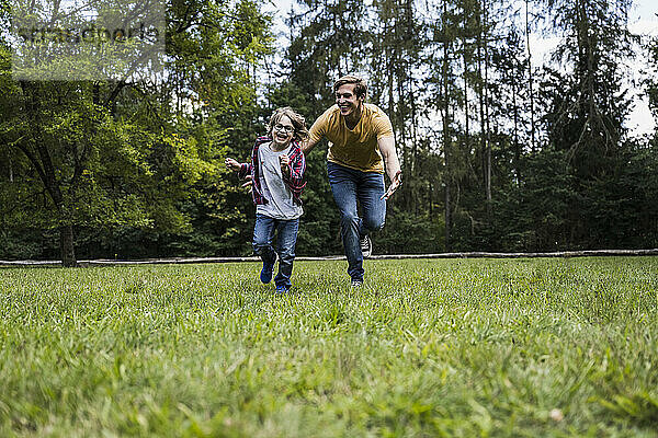 Verspielter Sohn und Vater laufen im Park auf Gras