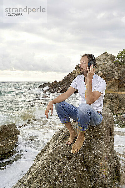 Mann hört am Strand Musik über Kopfhörer