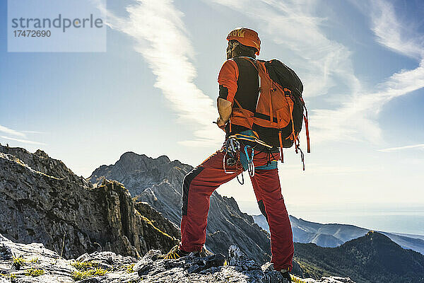 Männlicher Alpinist mit Rucksack steht auf dem Berg