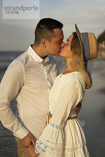Zärtliches junges Paar küsst sich am Strand auf den Mund