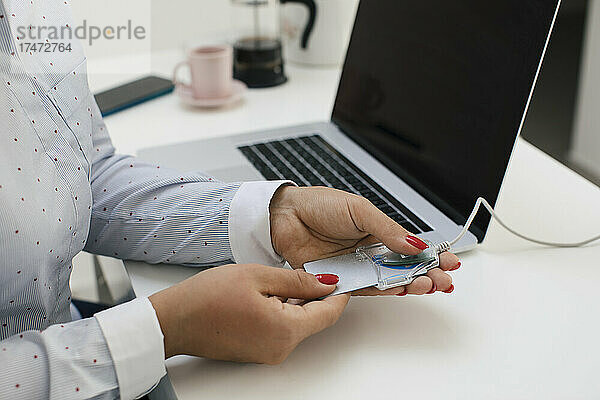 Freiberuflerin scannt Kreditkarte durch Lesegerät  während sie im Heimbüro arbeitet
