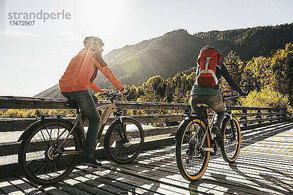 Paar fährt an einem sonnigen Tag Fahrrad an der Brücke