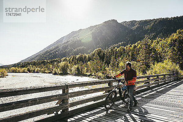 Mann schaut an einem sonnigen Tag auf den Fluss und fährt Fahrrad