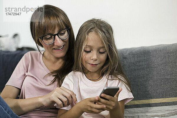 Mädchen benutzt Smartphone mit Frau zu Hause
