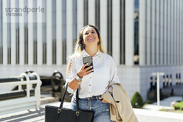 Glückliche Geschäftsfrau mit Smartphone  das nach oben schaut