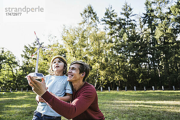 Vater hält Windturbinenmodell mit Sohn im Park