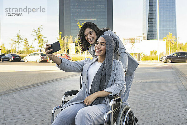 Lächelnde behinderte Geschäftsfrau macht ein Selfie mit einer Kollegin auf dem Fußweg