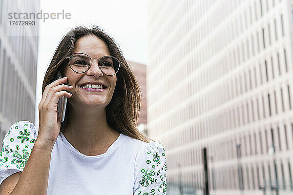 Glückliche junge Geschäftsfrau  die am Smartphone spricht