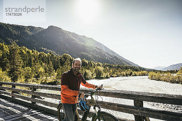 Lächelnder Mann  der Fahrrad auf Brücke dreht