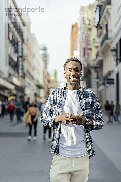 Junger Mann hält Smartphone auf der Stadtstraße