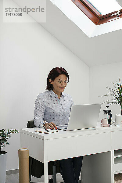 Geschäftsfrau nutzt Laptop  während sie freiberuflich im Heimbüro arbeitet