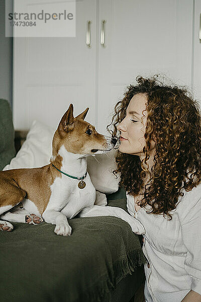 Frau mit lockigem Haar schaut Basenji-Hund an
