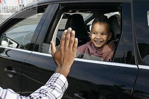 Vater gibt lächelndem Sohn im Auto High-Five