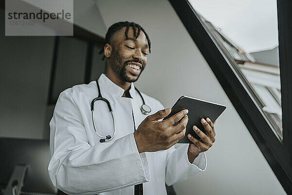 Lächelnder Arzt nutzt Tablet-PC im Büro
