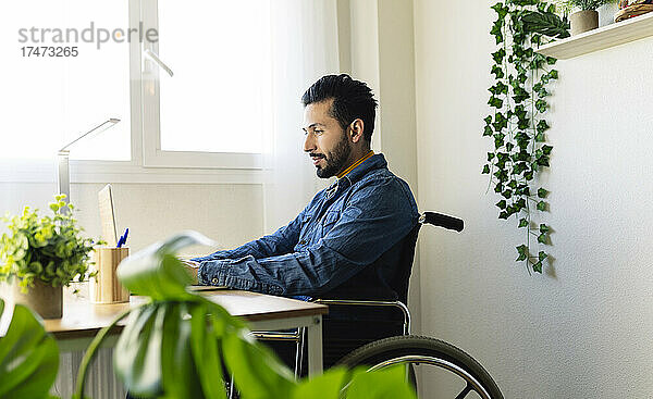 Behinderter Geschäftsmann  der zu Hause am Laptop arbeitet