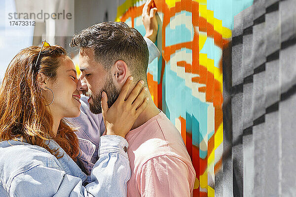 Paar küsst sich an einem sonnigen Tag an der Graffiti-Wand