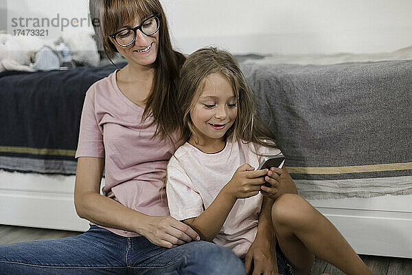 Tochter benutzt Smartphone mit Mutter zu Hause