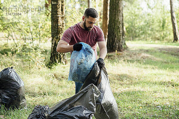 Männlicher Freiwilliger legt Abfall in Mülltüte