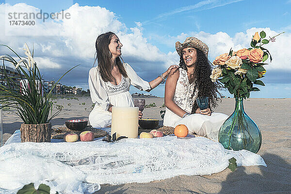 Fröhliche Freundinnen genießen Picknick am Strand