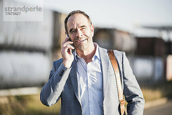 Lächelnder Geschäftsmann  der über Mobiltelefon spricht
