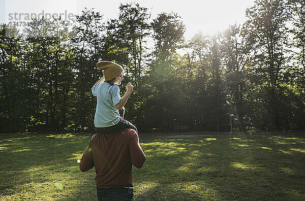 Vater trägt Sohn auf Schultern im Park