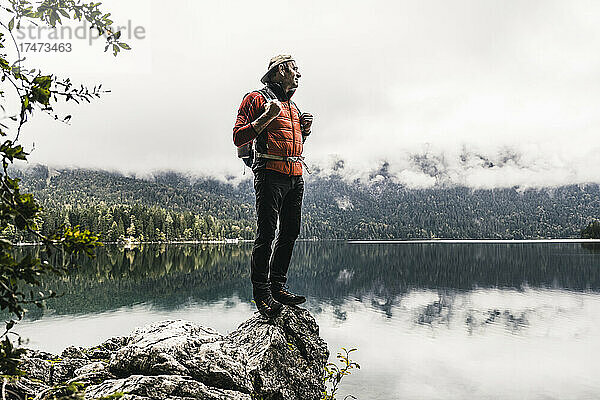 Mann mit Rucksack blickt auf See im Wald