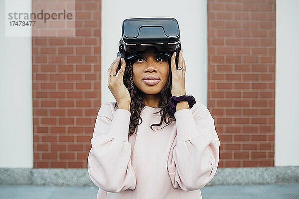 Frau hält Virtual-Reality-Headset vor der Wand