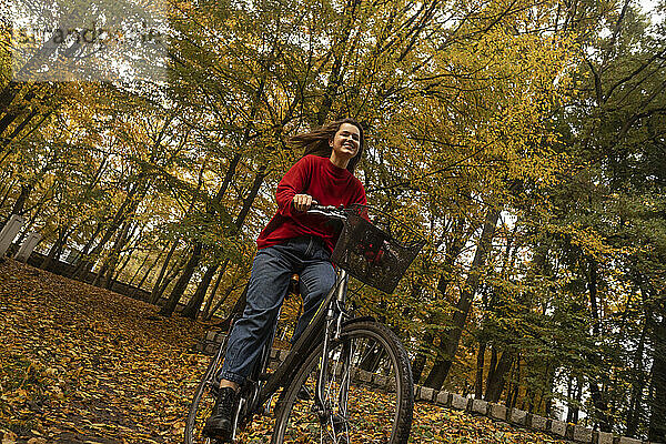Lächelnde Frau radelt im Herbstpark