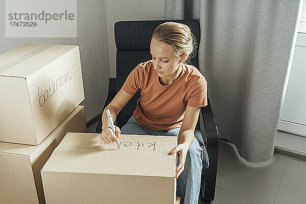 Frau schreibt zu Hause mit Filzstift auf Karton