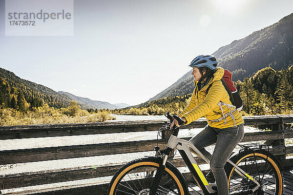 Frau mit Rucksack fährt Mountainbike auf Brücke