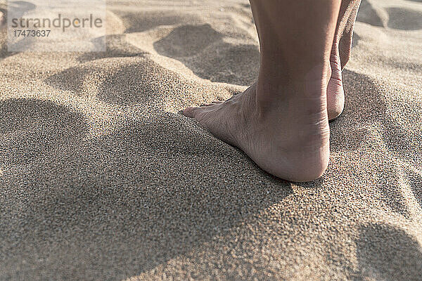 Reife Frau steht barfuß auf Sand