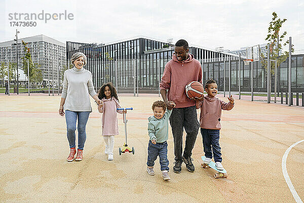 Lächelnde Familie geht gemeinsam auf dem Sportplatz spazieren