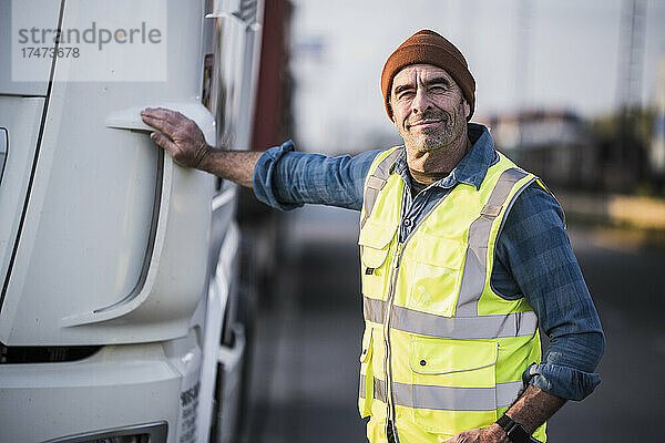 Lächelnder männlicher Fahrer  der neben dem LKW steht