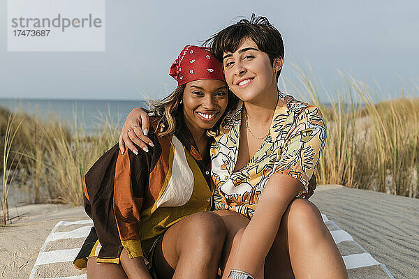 Lächelndes lesbisches Paar  das sich am Strand umarmt