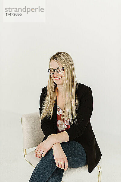 Lächelnde Fachfrau mit blonden Haaren  die auf einem Stuhl sitzt