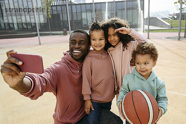 Vater macht Selfie mit Kindern per Handy am Sportplatz