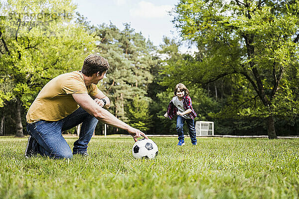 Mann und Junge spielen mit Fußball auf Gras
