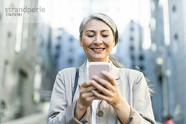 Lächelnde Frau  die Textnachrichten über das Smartphone sendet