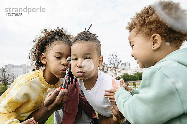 Glückliche Kinder  die im Park Seifenblasen blasen