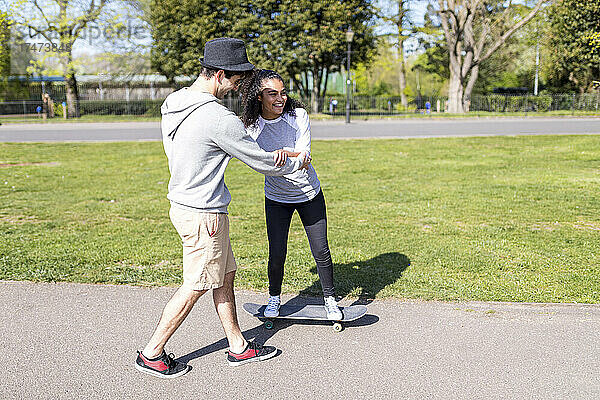 Mann hilft Freund beim Skateboarden im Park