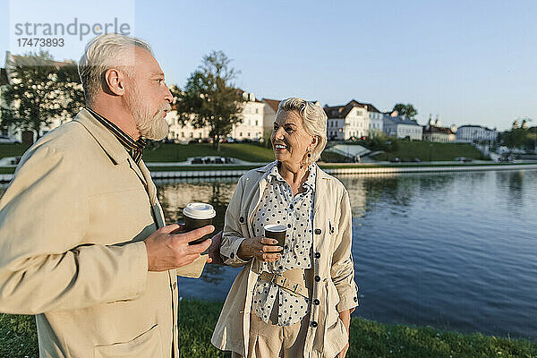Paar unterhält sich  während es eine Einwegkaffeetasse am Ufer hält