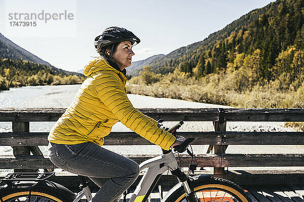 Frau mit Sturzhelm fährt an sonnigem Tag Mountainbike