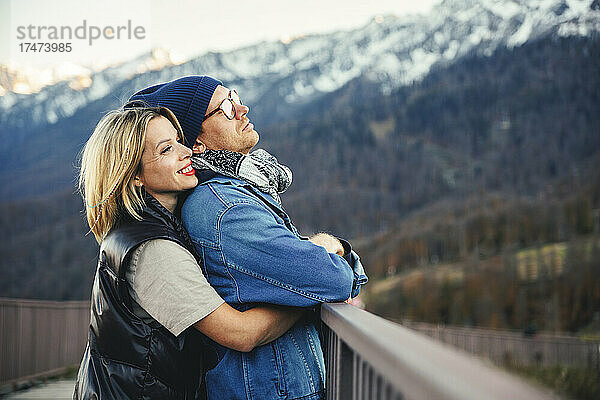 Lächelnde Frau umarmt Mann auf Brücke
