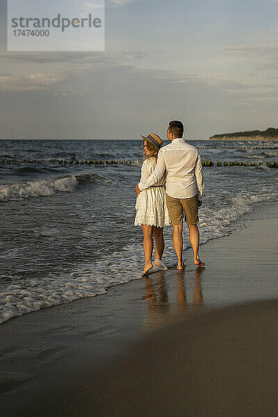Junges Paar steht zusammen am Strand