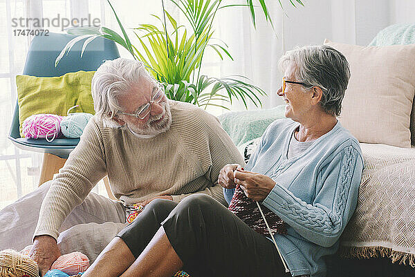 Älteres Paar mit Stricknadel sitzt im Wohnzimmer