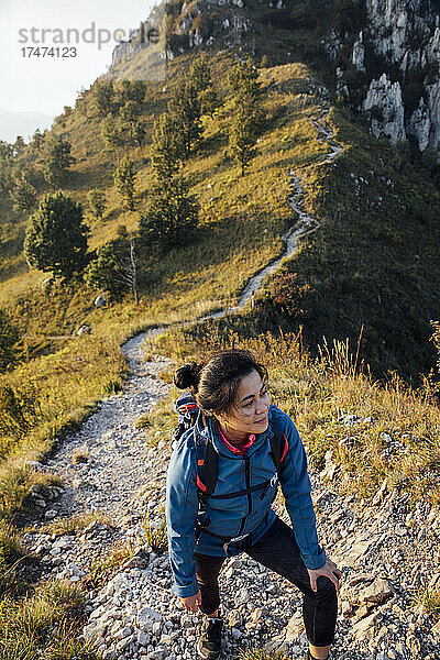 Junge Frau lächelt beim Wandern auf dem Berg