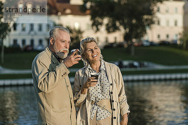Paar trinkt bei Sonnenuntergang Kaffee am Ufer