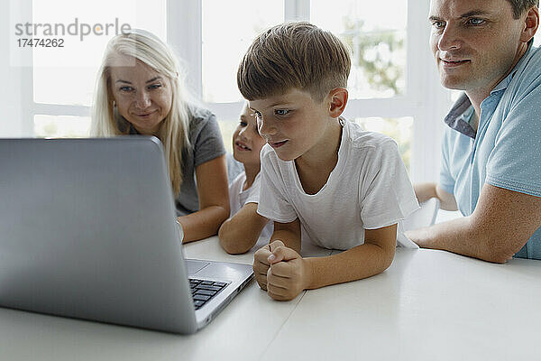 Familie schaut zu Hause auf den Laptop auf dem Tisch