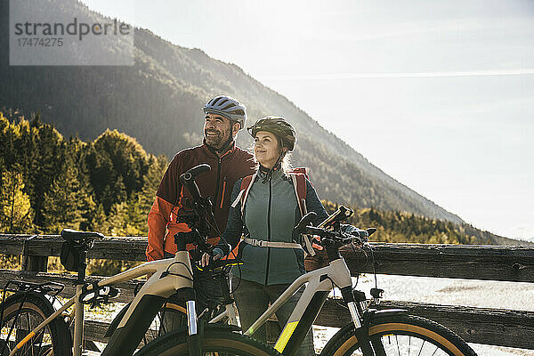 Lächelndes Paar steht mit Fahrrädern auf der Brücke